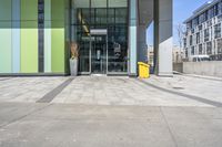 a yellow object sitting on the sidewalk next to the entrance to a large building in a city