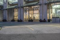 a parking lot and large windows in a city building at night with an electric car parked next to the curb