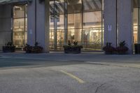 a parking lot and large windows in a city building at night with an electric car parked next to the curb