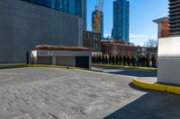 a parking lot with no cars on a sunny day next to tall buildings in the distance