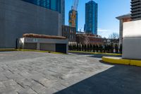 a parking lot with no cars on a sunny day next to tall buildings in the distance