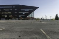 a parking lot near a large building has black paint on it and yellow lines on it