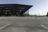 a parking lot near a large building has black paint on it and yellow lines on it