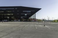 a parking lot near a large building has black paint on it and yellow lines on it