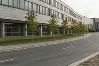 an asphalt road running through front of a building with a traffic light on the sidewalk