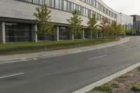 an asphalt road running through front of a building with a traffic light on the sidewalk