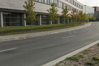 an asphalt road running through front of a building with a traffic light on the sidewalk