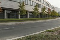 an asphalt road running through front of a building with a traffic light on the sidewalk