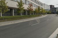 an asphalt road running through front of a building with a traffic light on the sidewalk