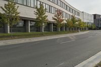 an asphalt road running through front of a building with a traffic light on the sidewalk