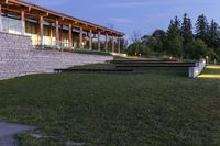 a large stone wall sitting in the middle of a grass field by a building with a walkway