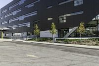 the front of the building has windows and a planter near the sidewalk on a side walk