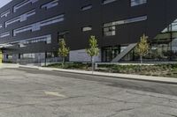 the front of the building has windows and a planter near the sidewalk on a side walk