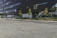 the front of the building has windows and a planter near the sidewalk on a side walk