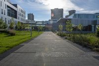 a city street surrounded by grass and tall buildings at the end of a street there is a paved pathway in front of the building