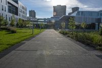 a city street surrounded by grass and tall buildings at the end of a street there is a paved pathway in front of the building