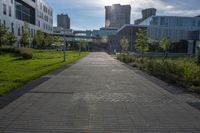 a city street surrounded by grass and tall buildings at the end of a street there is a paved pathway in front of the building