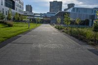 a city street surrounded by grass and tall buildings at the end of a street there is a paved pathway in front of the building