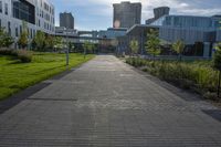 a city street surrounded by grass and tall buildings at the end of a street there is a paved pathway in front of the building