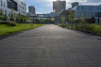 a city street surrounded by grass and tall buildings at the end of a street there is a paved pathway in front of the building