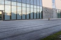 a yellow fire hydrant is sitting in front of the large building with the glass windows