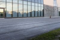 a yellow fire hydrant is sitting in front of the large building with the glass windows