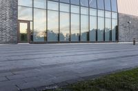 a yellow fire hydrant is sitting in front of the large building with the glass windows