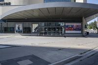 a person sitting at the bench in front of a mall that is empty of people