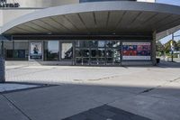 a person sitting at the bench in front of a mall that is empty of people