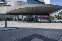 a person sitting at the bench in front of a mall that is empty of people