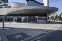 a person sitting at the bench in front of a mall that is empty of people