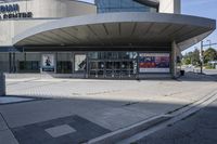 a person sitting at the bench in front of a mall that is empty of people