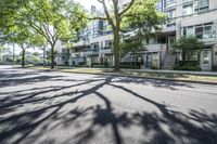 a tree lined sidewalk next to two tall buildings in a residential area surrounded by tall trees