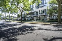 a tree lined sidewalk next to two tall buildings in a residential area surrounded by tall trees