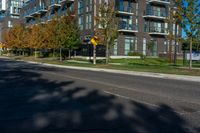 an apartment building on a street corner with trees growing in the grass beside it and a stoplight