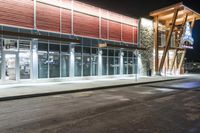 a store front at night with cars and lights outside it and the glass walls at the front