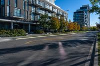 an empty street in a modern city with tall buildings in the background and blue sky above