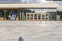 a double entrance way with wooden doors and glass walls on the building side area, while the walkway has a concrete pathway running through it