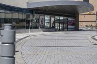 a person sitting at the bench in front of a mall that is empty of people