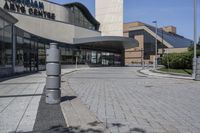 a person sitting at the bench in front of a mall that is empty of people