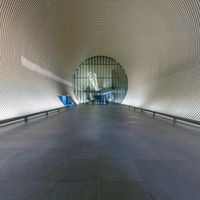 an inside looking tunnel with concrete floors and curved walls at the entrance of a train station