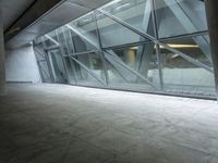 a photo inside an open space with large windows looking outside and empty flooring with white marble tile