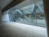 a photo inside an open space with large windows looking outside and empty flooring with white marble tile