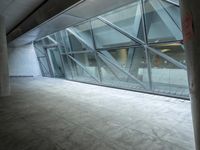 a photo inside an open space with large windows looking outside and empty flooring with white marble tile