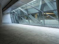 a photo inside an open space with large windows looking outside and empty flooring with white marble tile