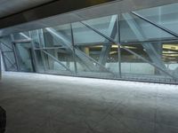 a photo inside an open space with large windows looking outside and empty flooring with white marble tile