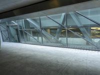 a photo inside an open space with large windows looking outside and empty flooring with white marble tile