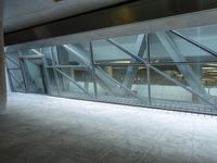 a photo inside an open space with large windows looking outside and empty flooring with white marble tile