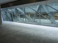 a photo inside an open space with large windows looking outside and empty flooring with white marble tile