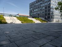 a long stairway leads up to the top of an outdoor park and plaza with landscaping along one side of the stairs